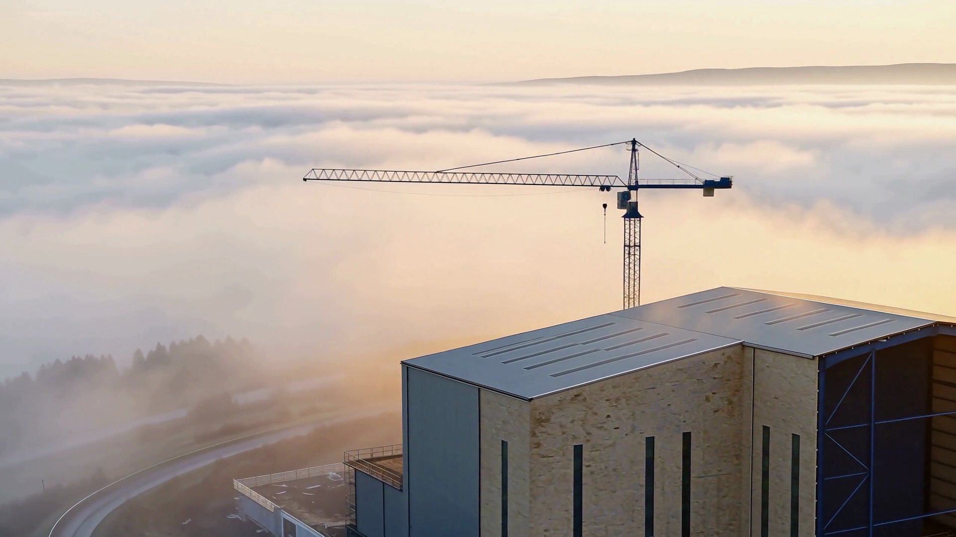 Morning fog clearing over a completed industrial building in a South Wales valley — illustrative brand imagery
